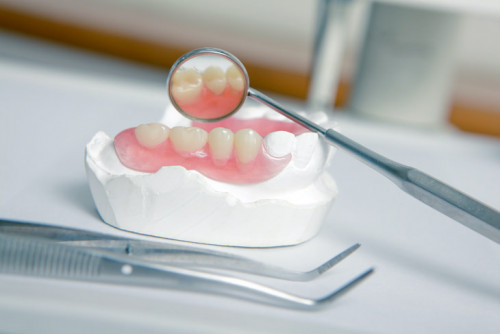 Metallic dentist tools with acrylic denture (False teeth) close up on a dentist chair in Dentist Cli